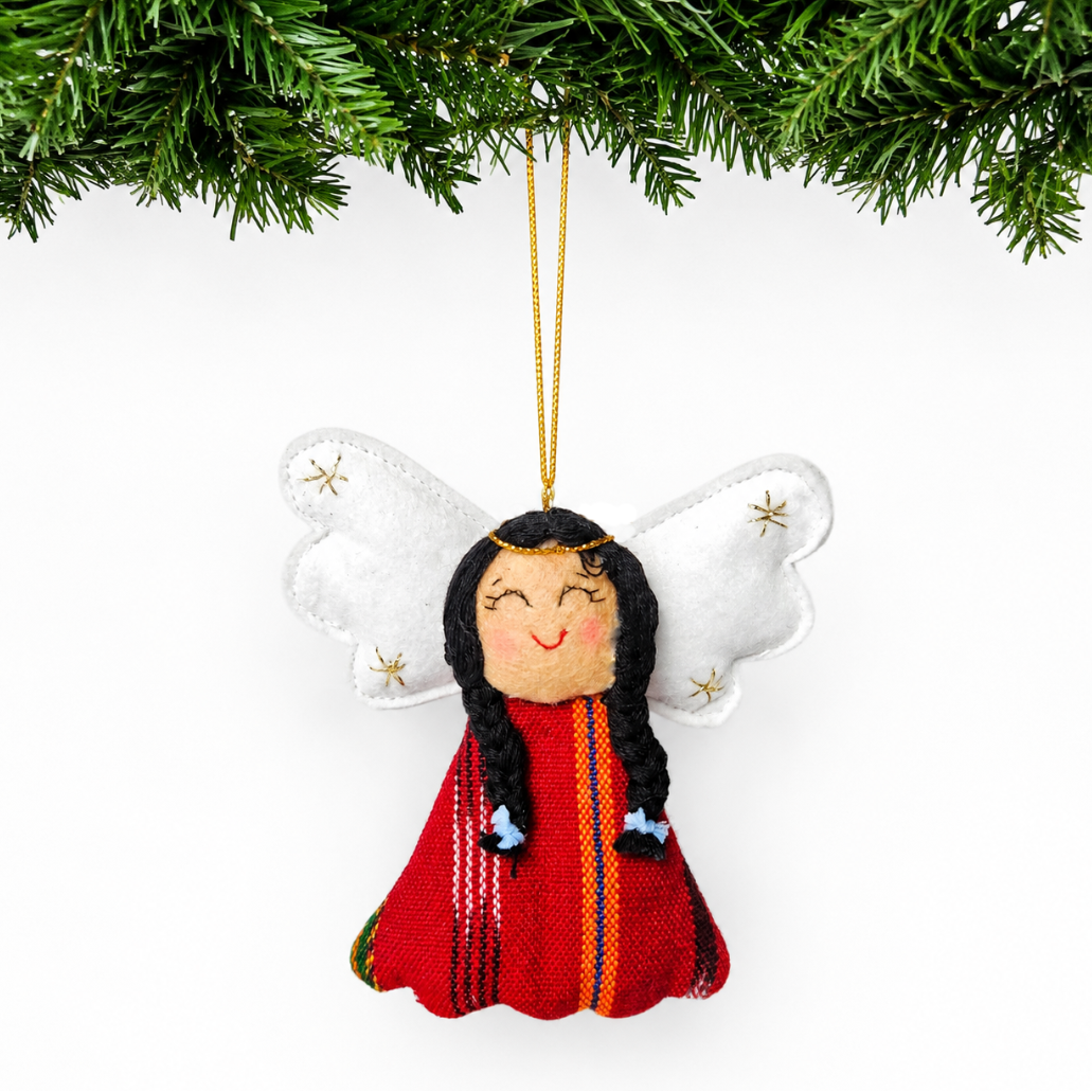 Decorative angel ornament with long hair and red outfit hanging from a tree branch.